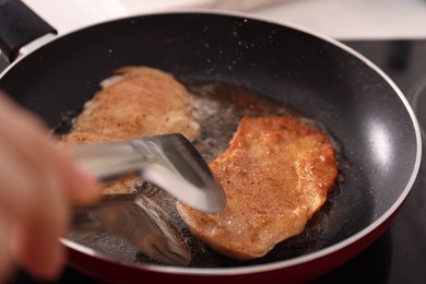 Photo of Woman cooking schnitzels in frying pan on stove, closeup