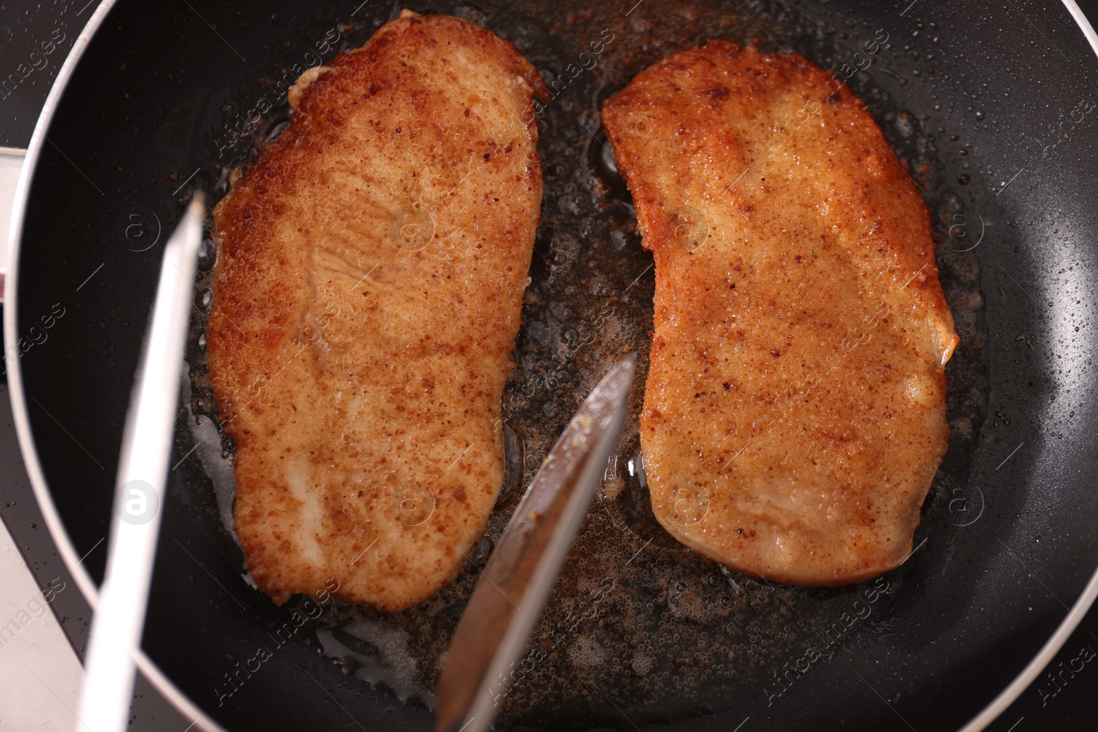 Photo of Schnitzels cooking in frying pan on stove, top view