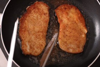 Schnitzels cooking in frying pan on stove, top view