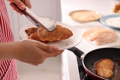 Photo of Woman cooking schnitzels in frying pan on stove, closeup