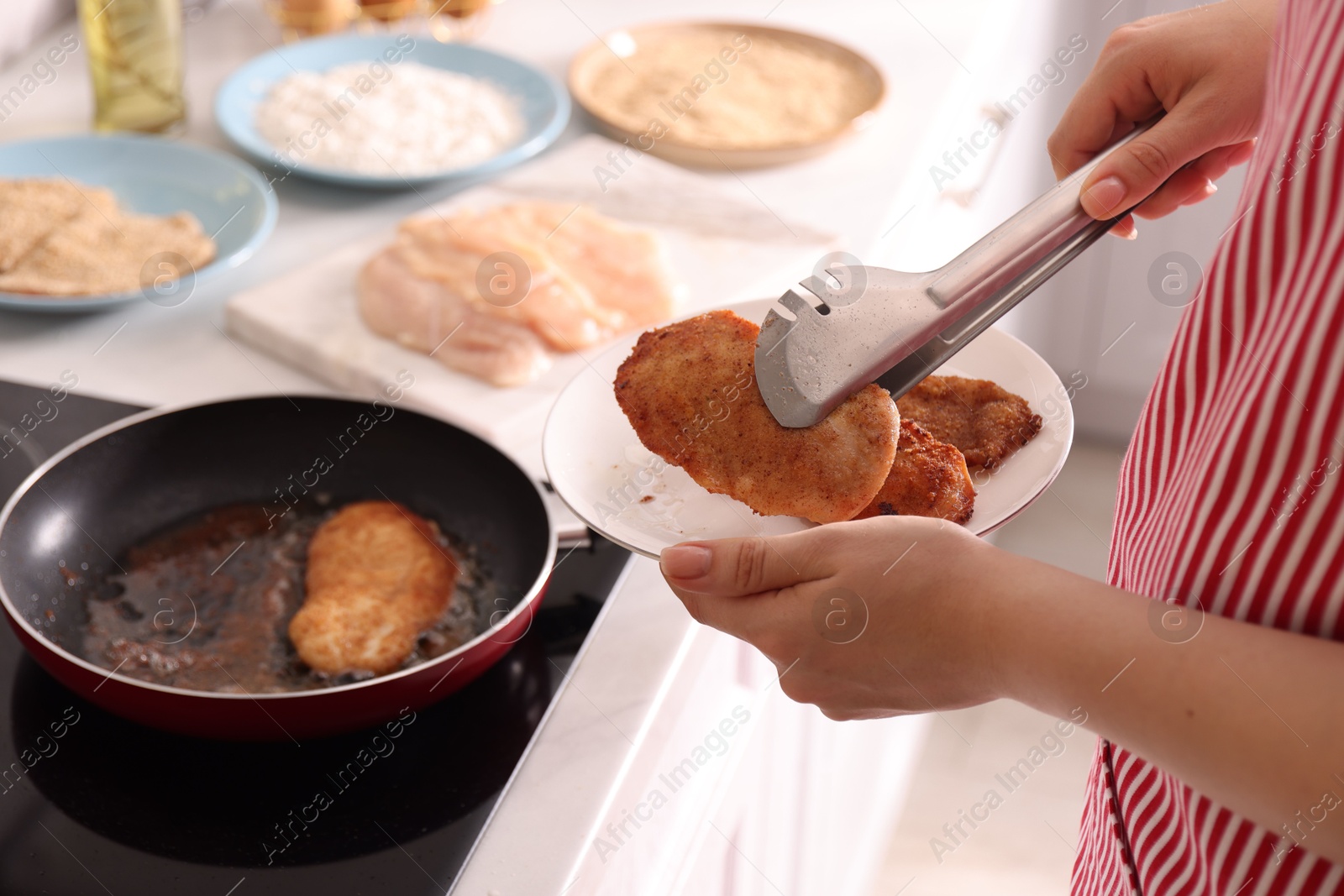 Photo of Woman cooking schnitzels in frying pan on stove, closeup