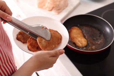 Photo of Woman cooking schnitzels in frying pan on stove, closeup