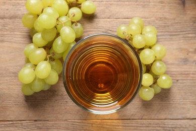 Tasty juice in glass and fresh grapes on wooden table, top view