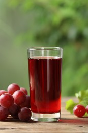 Tasty juice in glass and fresh grapes on wooden table