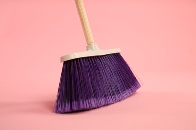 Photo of One bright cleaning broom on pink background