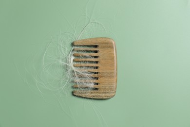 Photo of Comb with lost hair on green background, top view