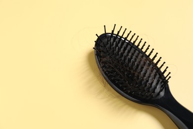 Photo of Brush with lost hair on yellow background, space for text