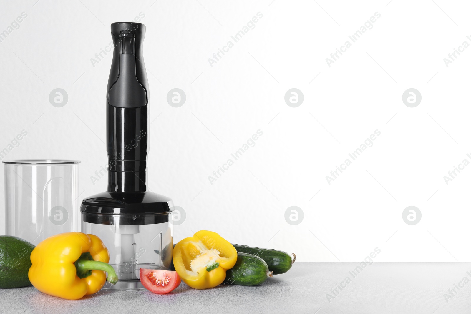 Photo of Hand blender kit and fresh vegetables on gray table against white background, space for text