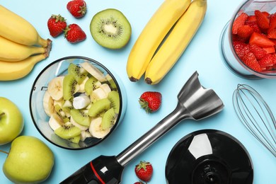 Hand blender kit, fresh fruits and strawberries on light blue background, flat lay