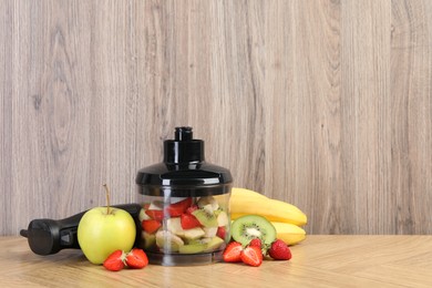 Hand blender kit, fresh fruits and strawberries on wooden table, space for text