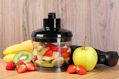 Photo of Hand blender kit, fresh fruits and strawberries on wooden table