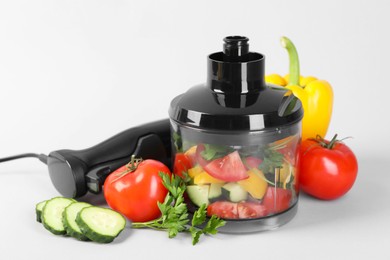 Photo of Hand blender kit, fresh vegetables and parsley on white background