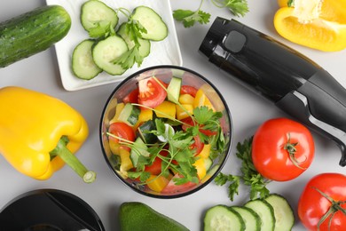 Hand blender kit, fresh vegetables and parsley on light background, flat lay