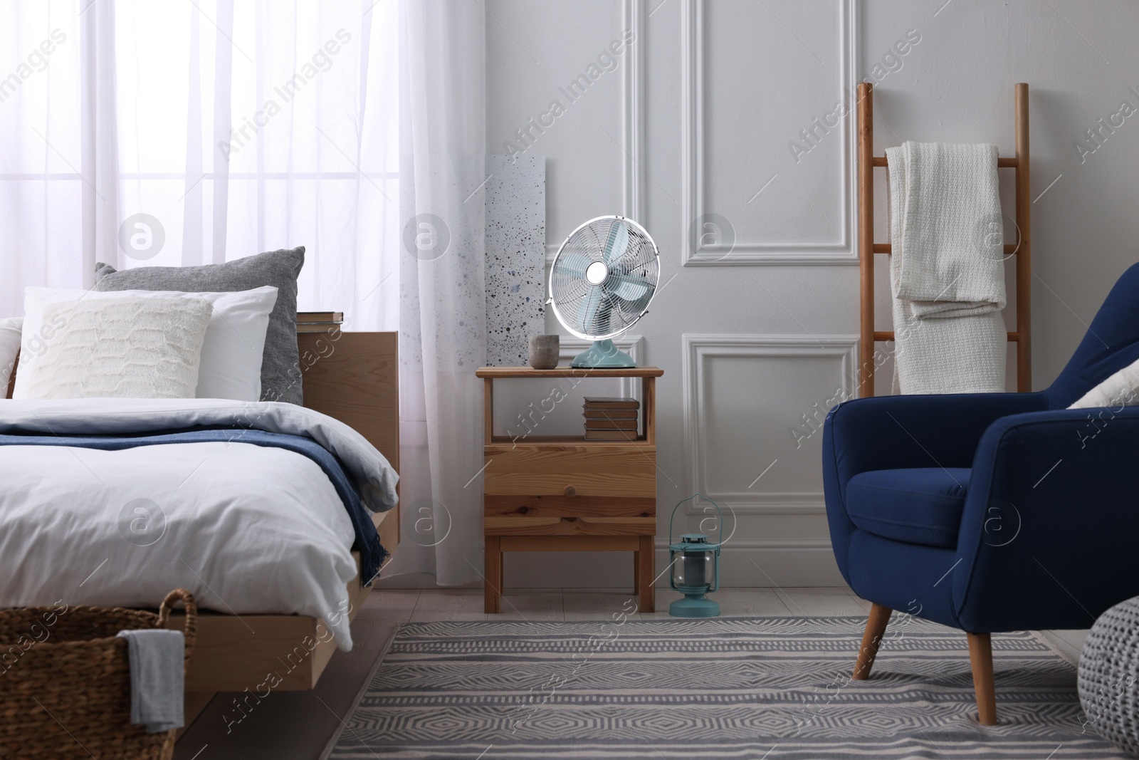 Photo of Stylish living room interior with bed, bedside table and fan