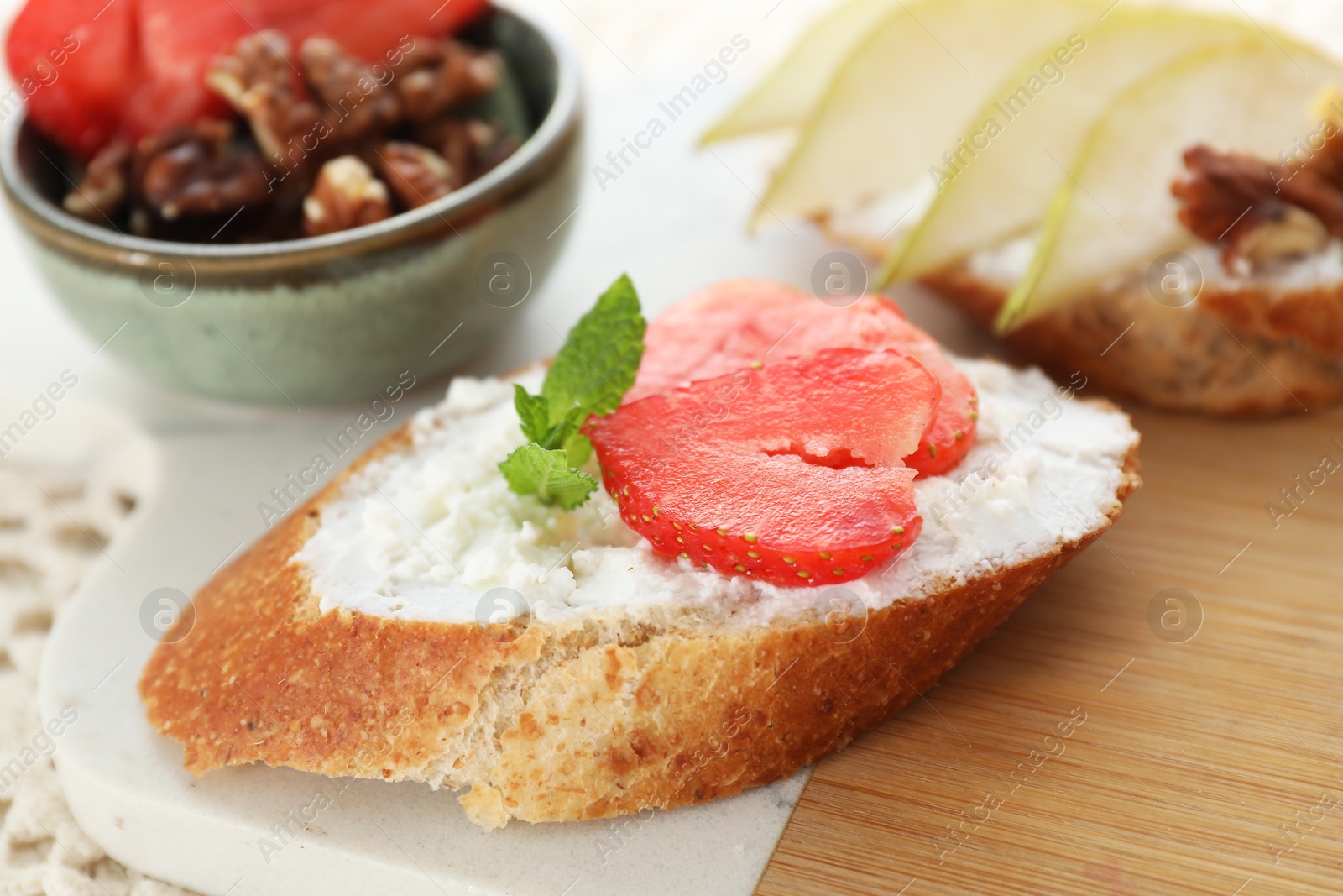 Photo of Delicious bruschetta with fresh ricotta (cream cheese), strawberry and mint on table, closeup