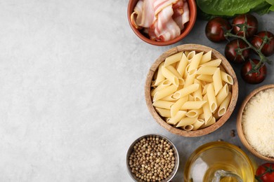 Photo of Raw pasta, bacon and fresh ingredients on light grey table, flat lay. Space for text