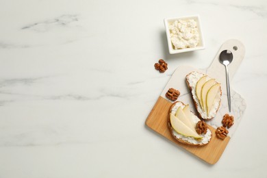 Delicious ricotta bruschettas with pear and walnut on white marble table, flat lay. Space for text