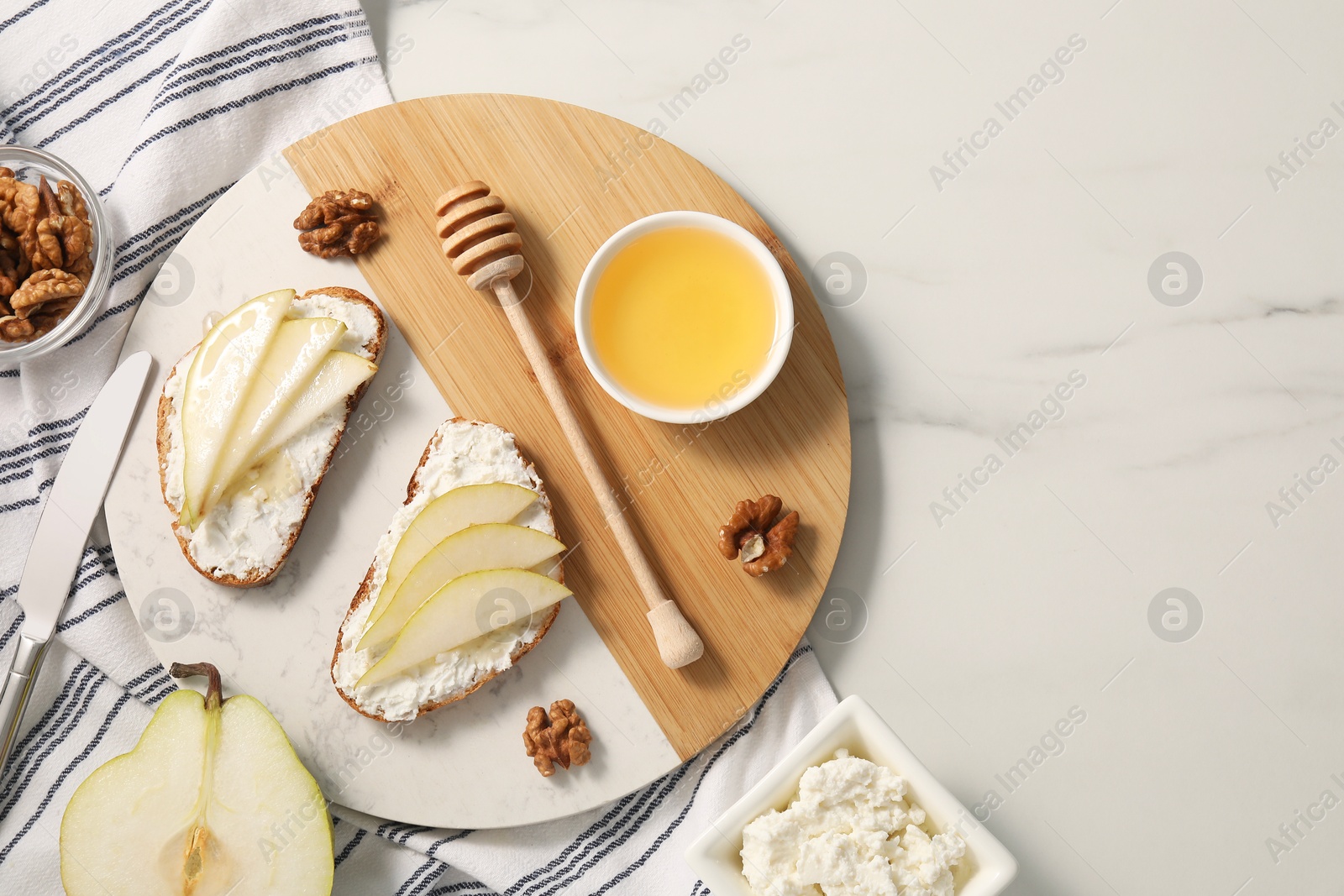 Photo of Delicious ricotta bruschettas with pear and walnut on white table, flat lay. Space for text