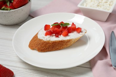 Photo of Delicious ricotta bruschetta with strawberry and mint on white wooden table