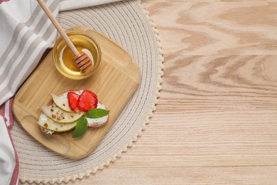 Photo of Delicious ricotta bruschetta with pear, strawberry and walnut on wooden table, flat lay. Space for text