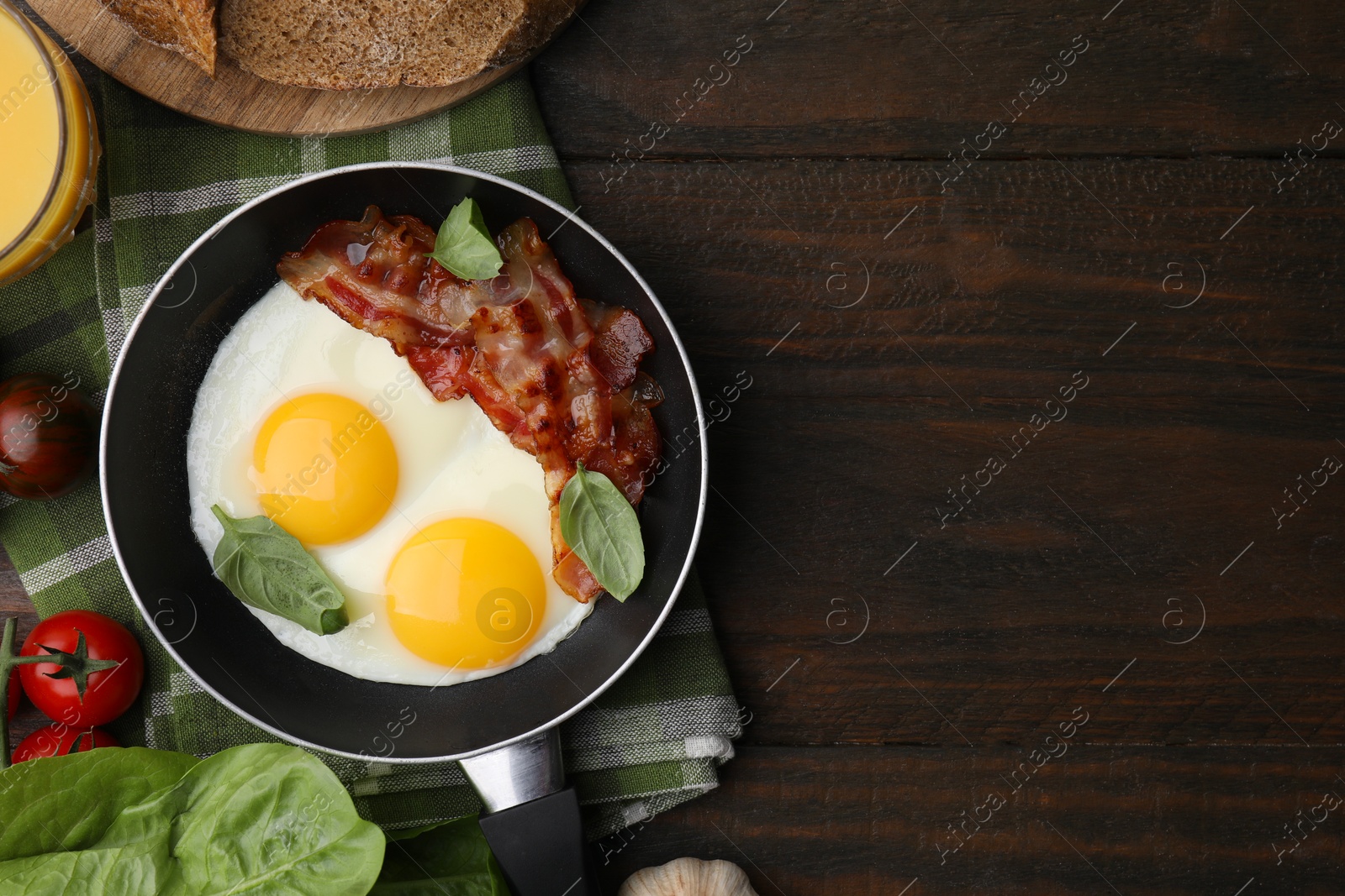 Photo of Fried eggs and bacon served on wooden table, top view. Space for text