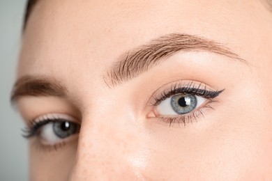 Photo of Young woman with beautiful eyebrows on light background, closeup