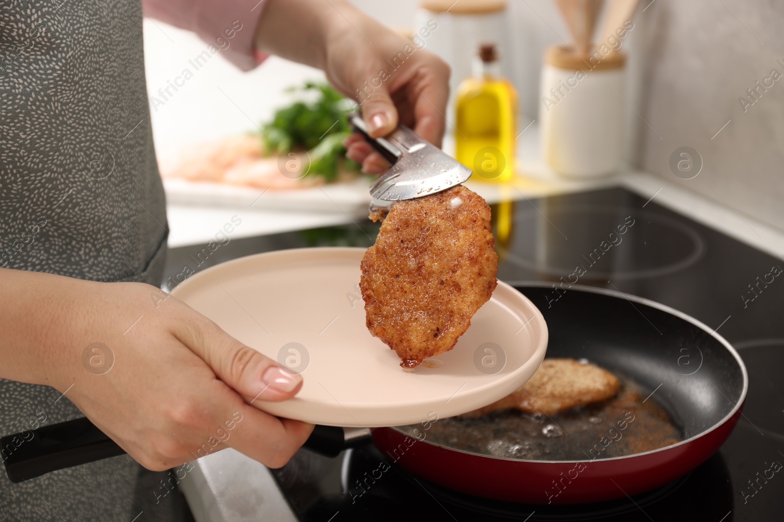 Photo of Woman cooking schnitzels in frying pan on stove, closeup