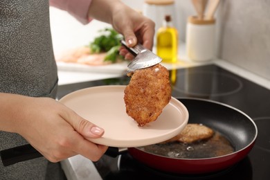 Woman cooking schnitzels in frying pan on stove, closeup