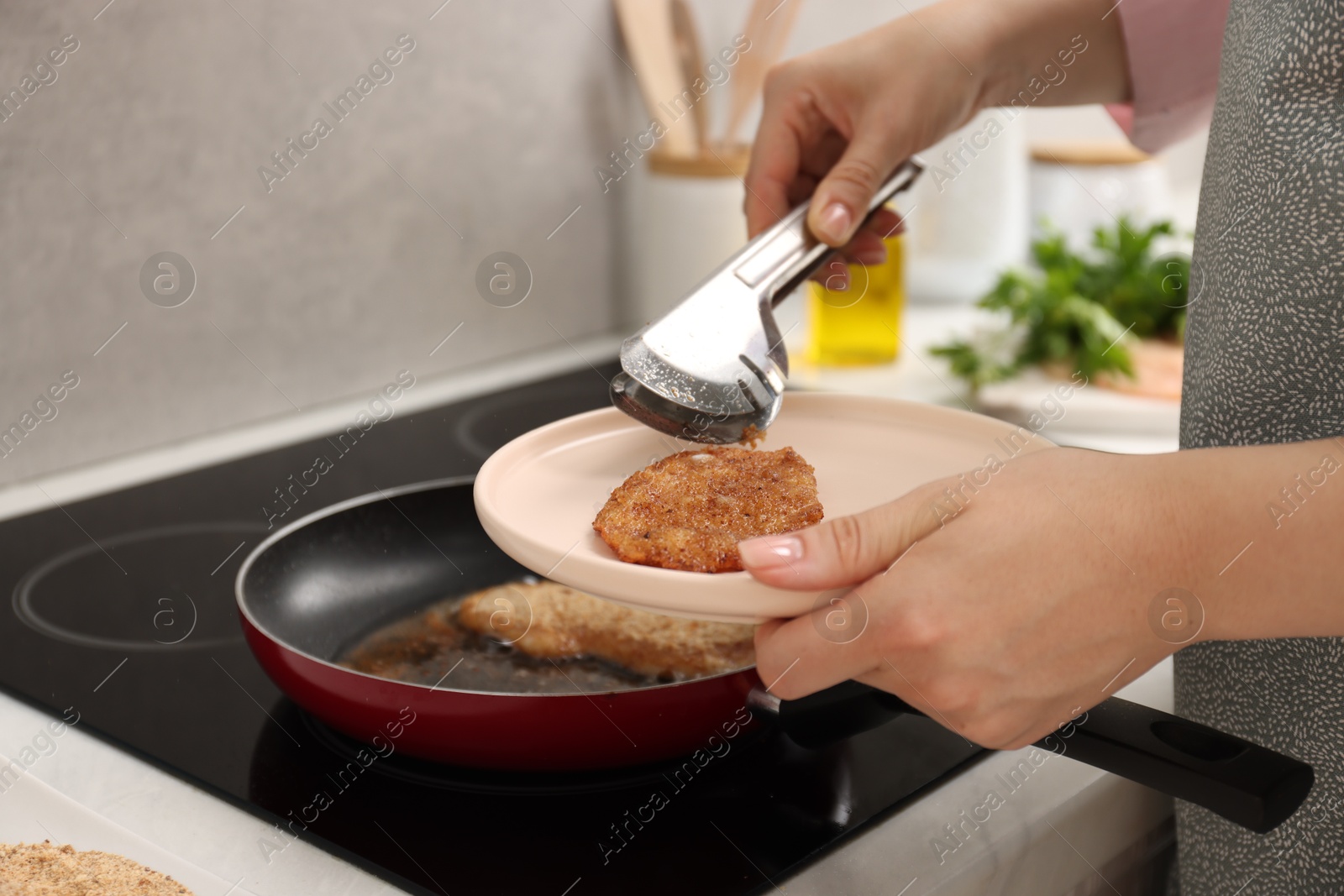 Photo of Woman cooking schnitzels in frying pan on stove, closeup