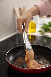 Woman cooking schnitzel in frying pan on stove, closeup