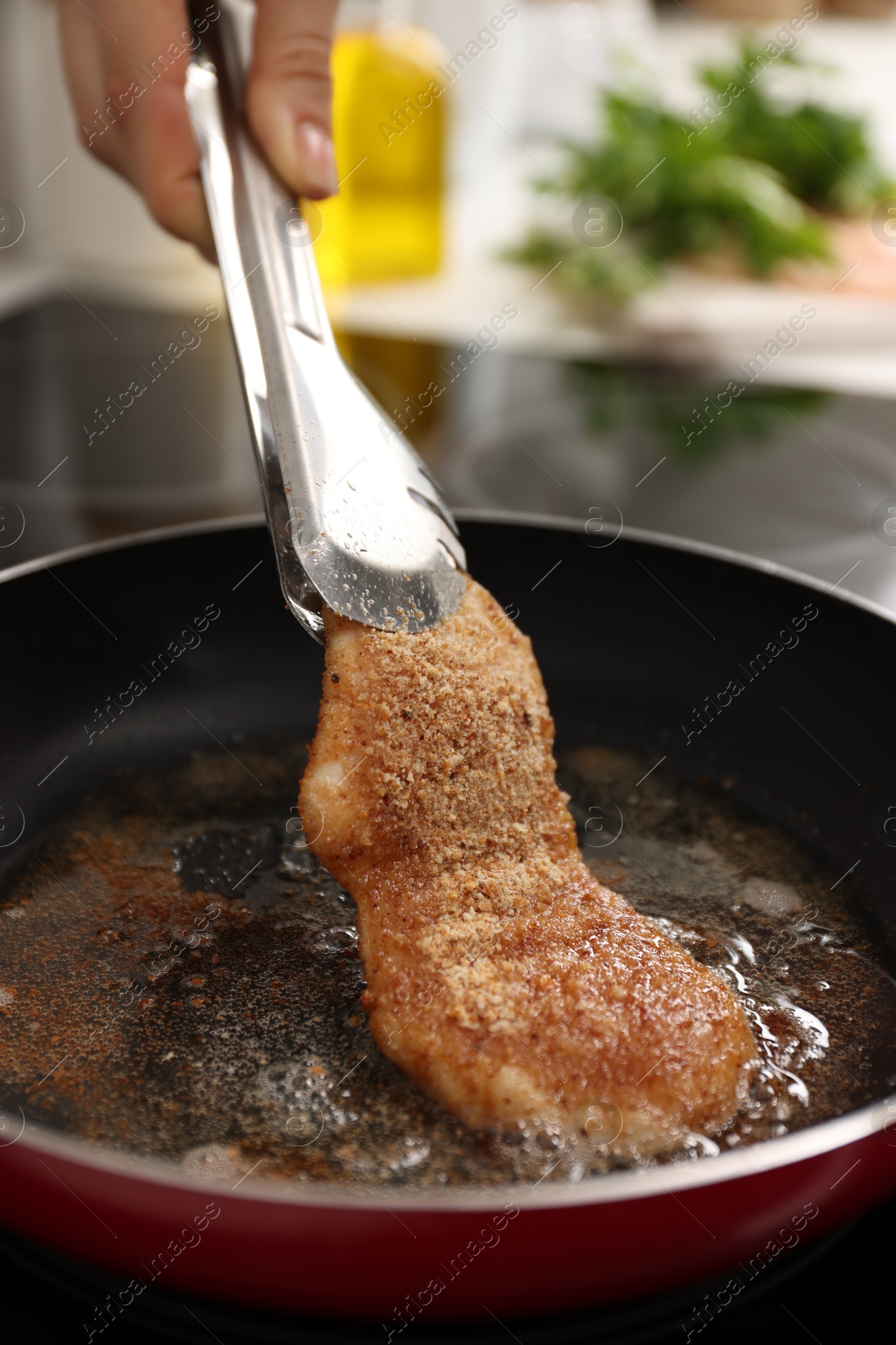 Photo of Woman cooking schnitzel in frying pan on stove, closeup