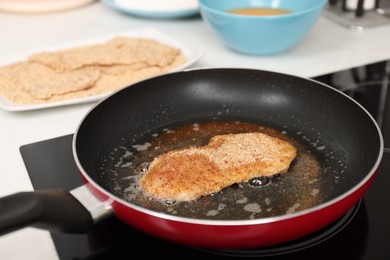 Photo of Cooking schnitzel in frying pan on stove, closeup