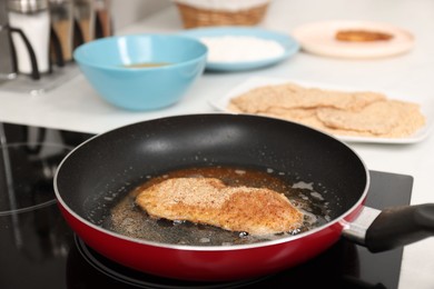 Photo of Cooking schnitzel in frying pan on stove, closeup