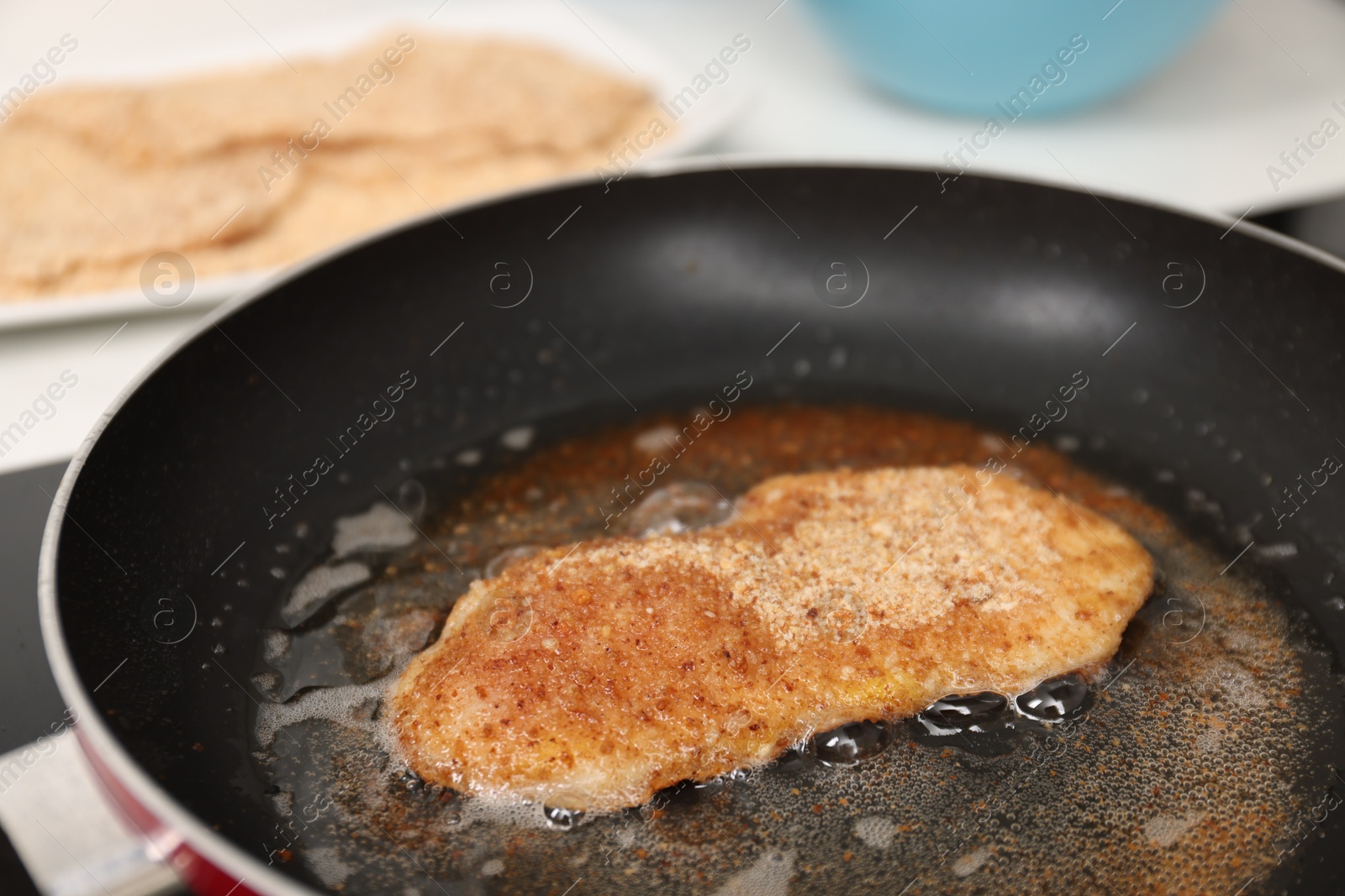 Photo of Cooking schnitzel in frying pan on stove, closeup