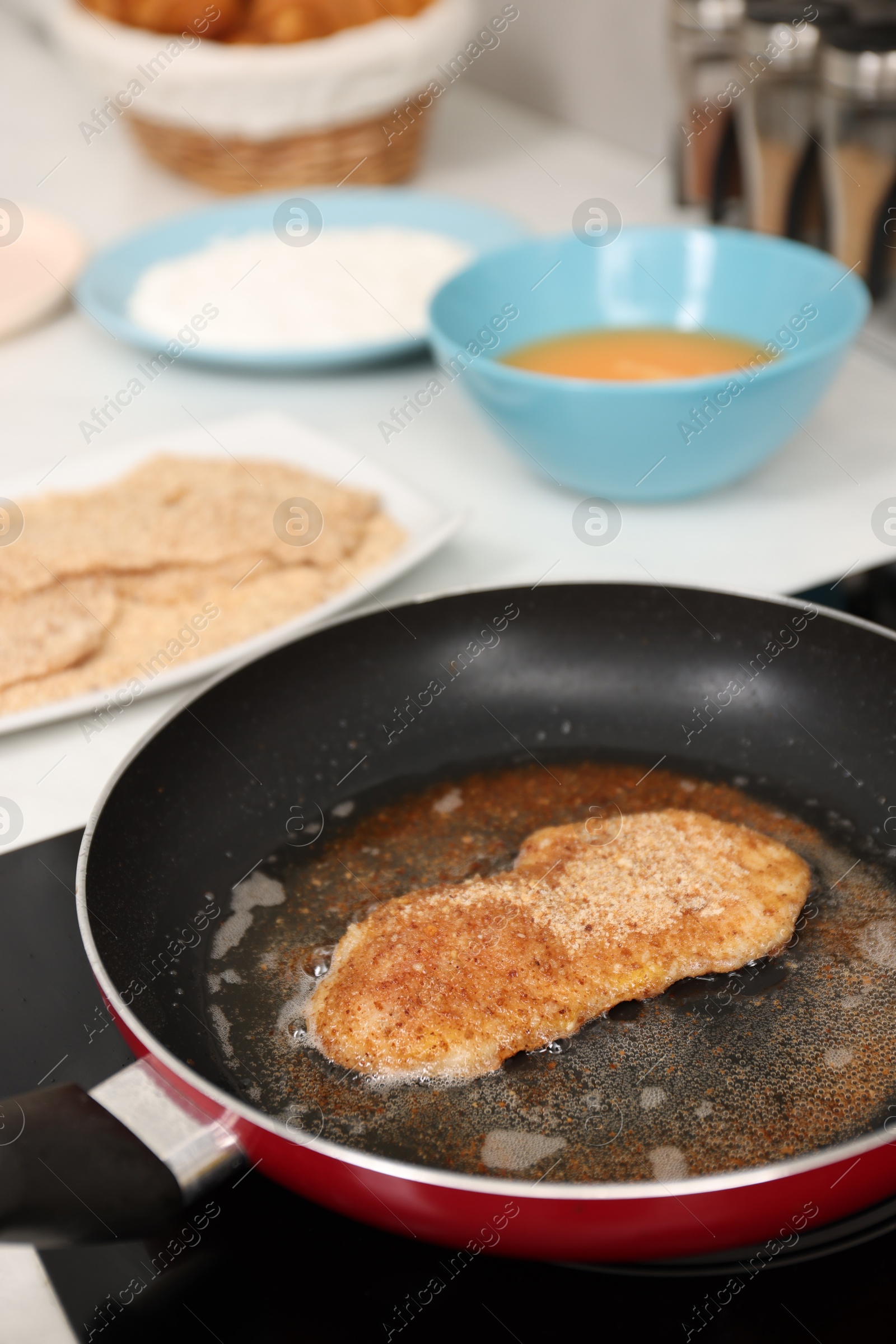 Photo of Cooking schnitzel in frying pan on stove, closeup