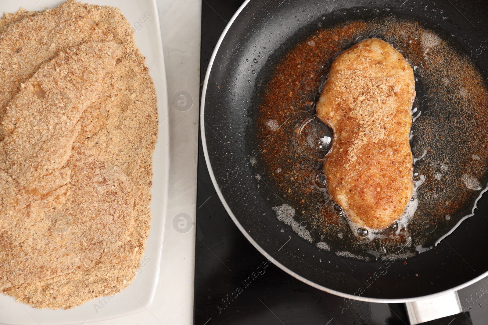 Photo of Schnitzel cooking in frying pan on stove, top view