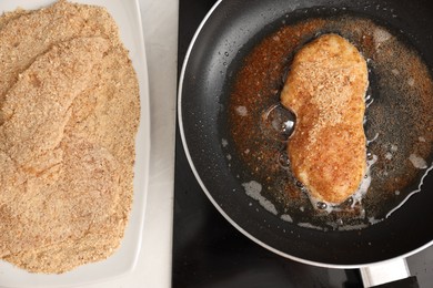 Schnitzel cooking in frying pan on stove, top view