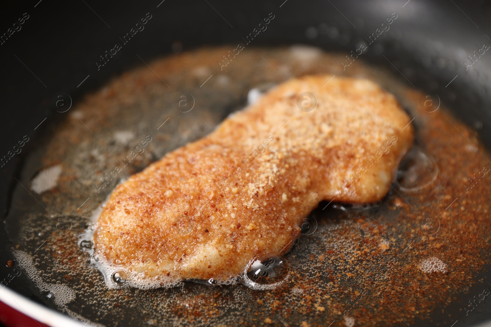 Photo of Cooking schnitzel in frying pan on stove, closeup