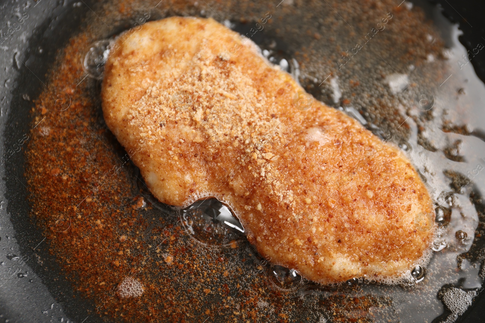 Photo of Cooking schnitzel in frying pan on stove, closeup