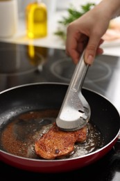 Woman cooking schnitzel in frying pan on stove, closeup