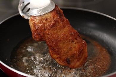 Photo of Cooking schnitzel in frying pan on stove, closeup