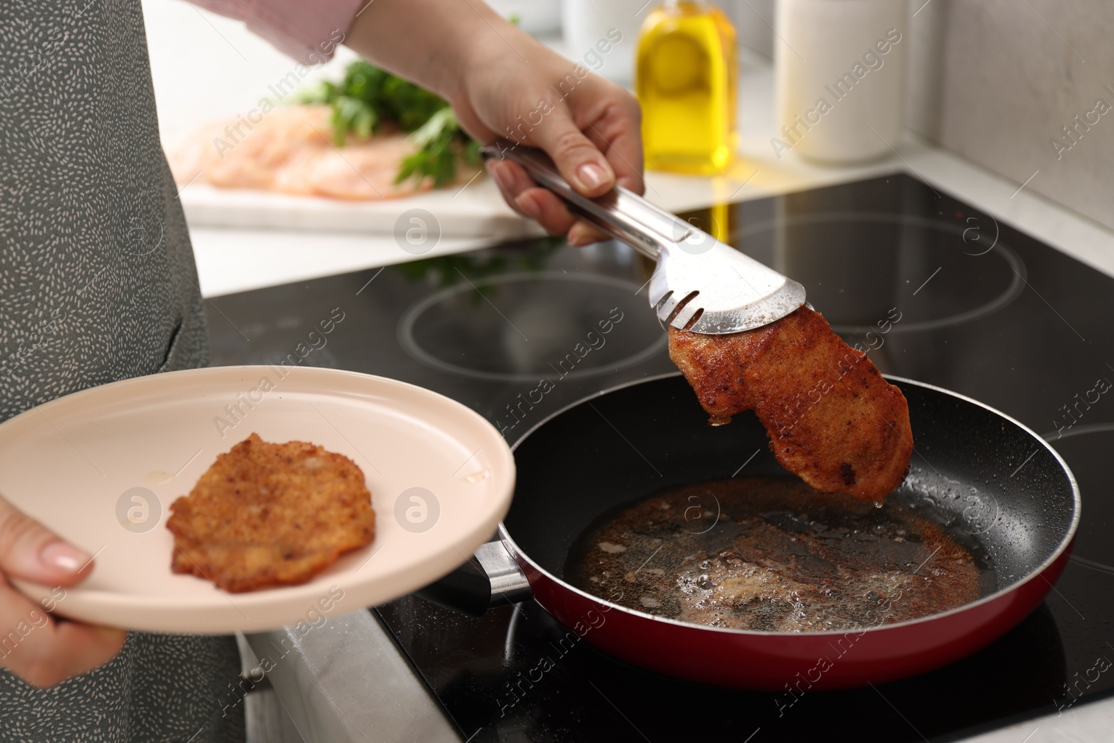 Photo of Woman cooking schnitzel in frying pan on stove, closeup