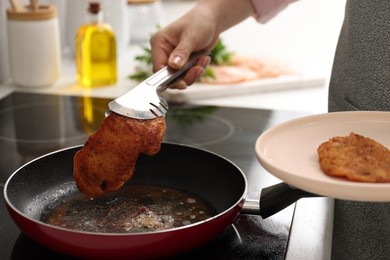 Photo of Woman cooking schnitzel in frying pan on stove, closeup