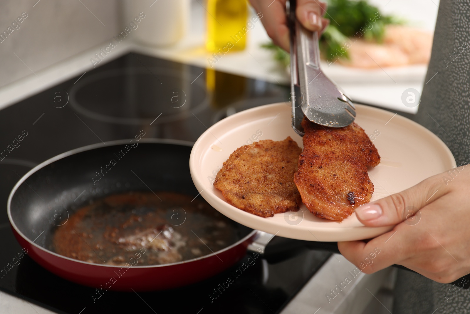 Photo of Woman cooking schnitzel in frying pan on stove, closeup