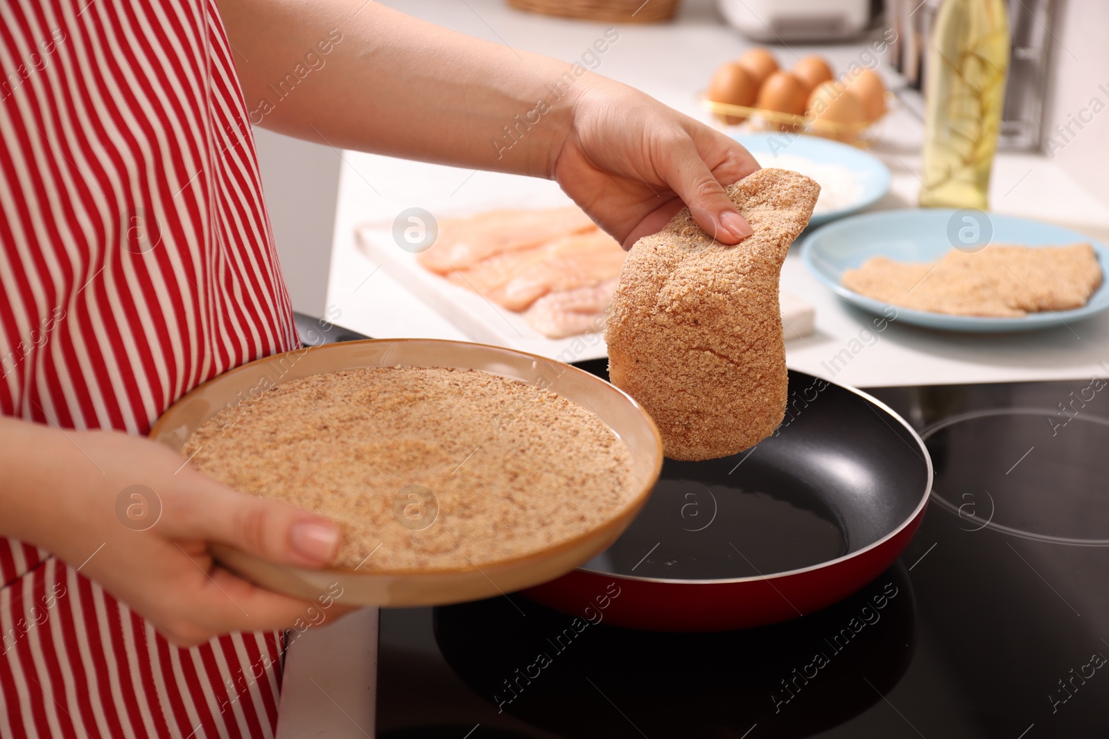 Photo of Woman cooking schnitzel in frying pan on stove, closeup