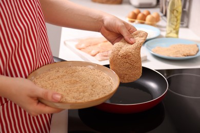 Woman cooking schnitzel in frying pan on stove, closeup