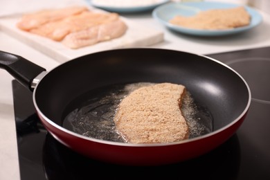 Photo of Cooking schnitzel in frying pan on stove, closeup