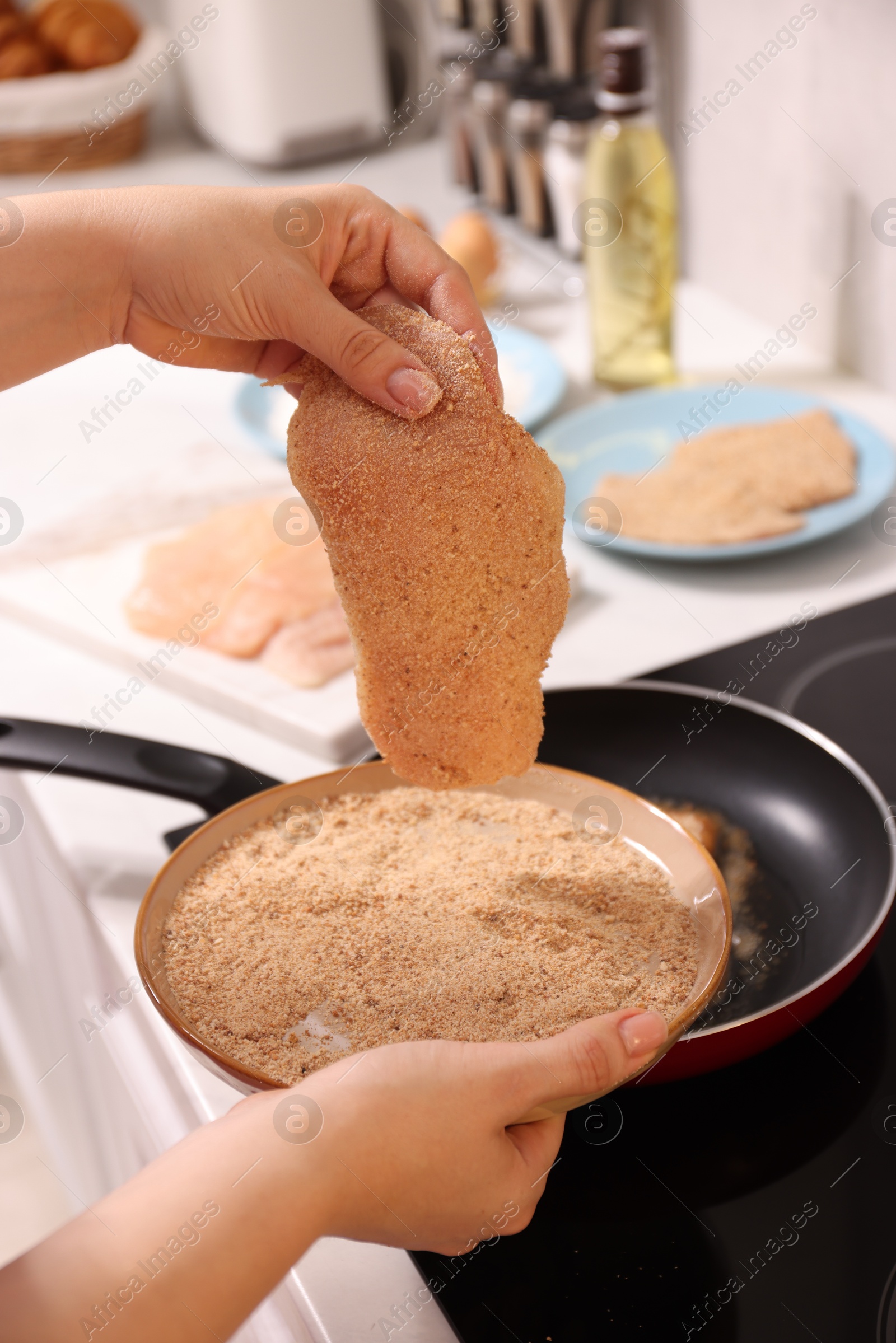 Photo of Woman cooking schnitzels in frying pan on stove, closeup