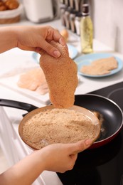 Woman cooking schnitzels in frying pan on stove, closeup