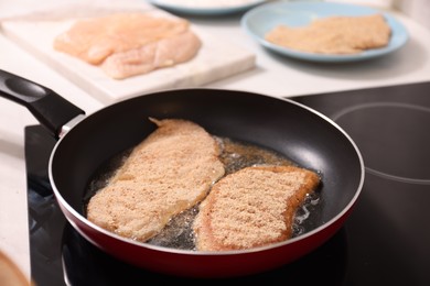 Cooking schnitzel in frying pan on stove, closeup